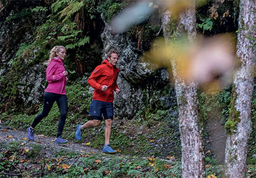 A man and woman trail running